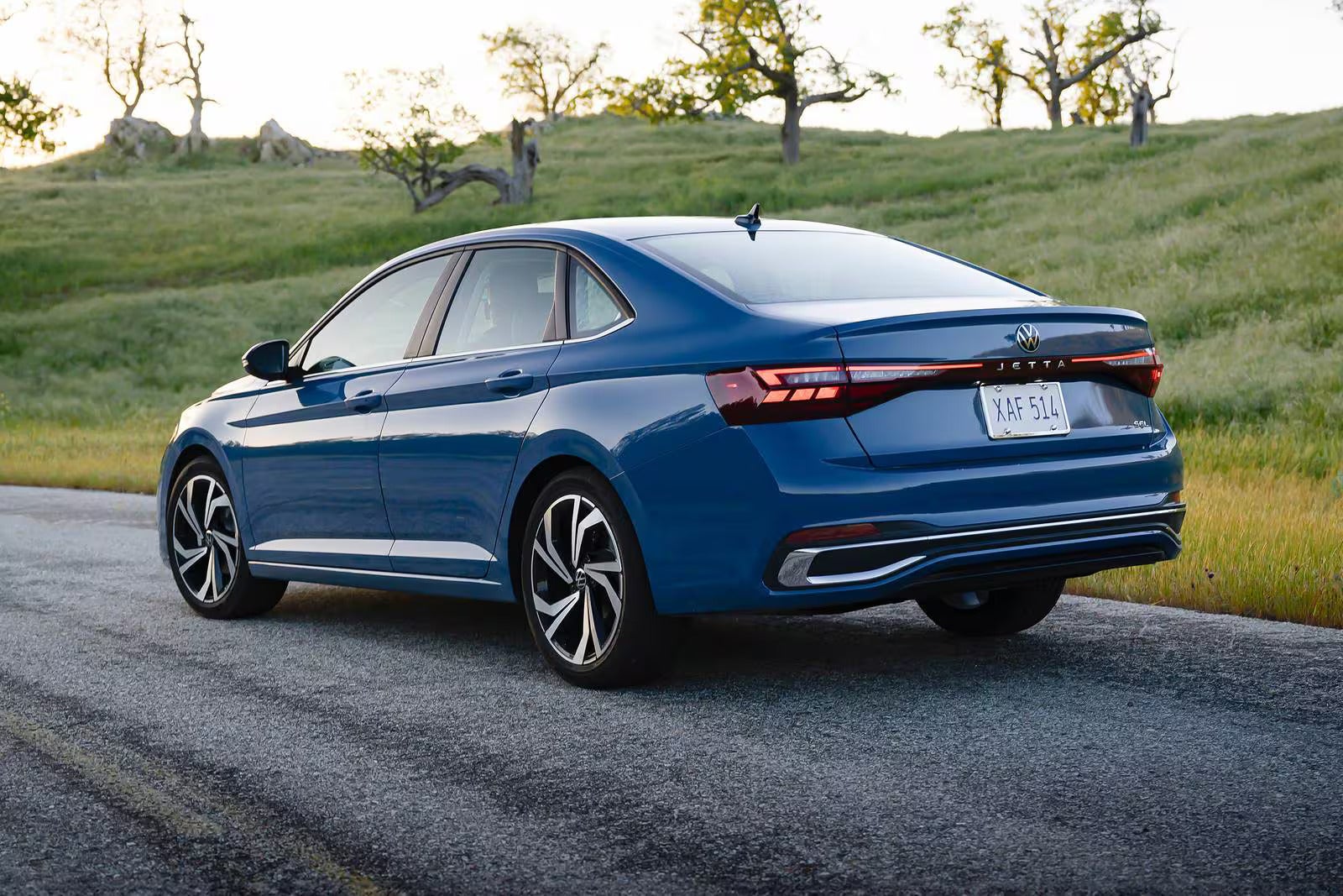 A blue jetta sitting in the road.