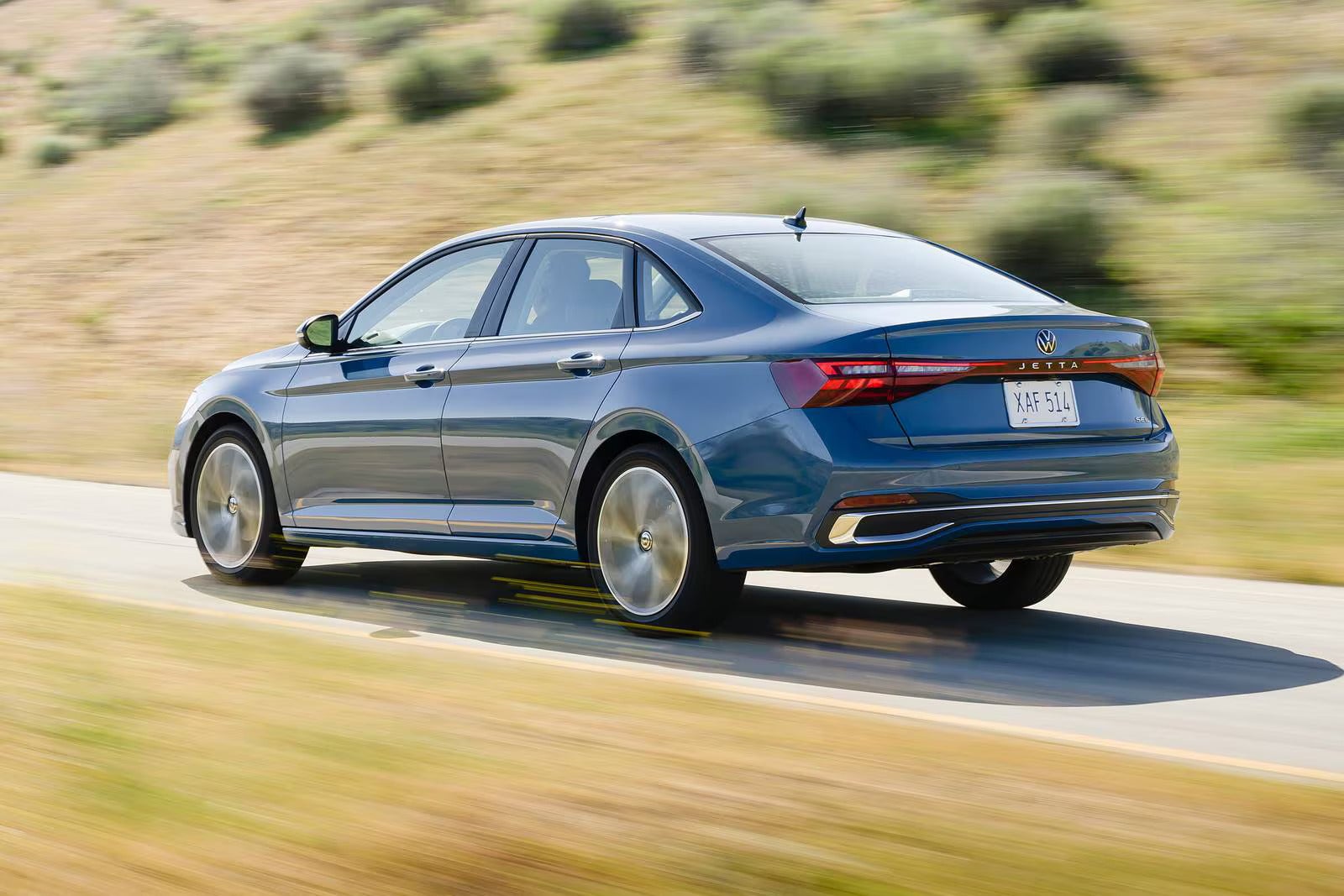 A blue jetta driving on the road.