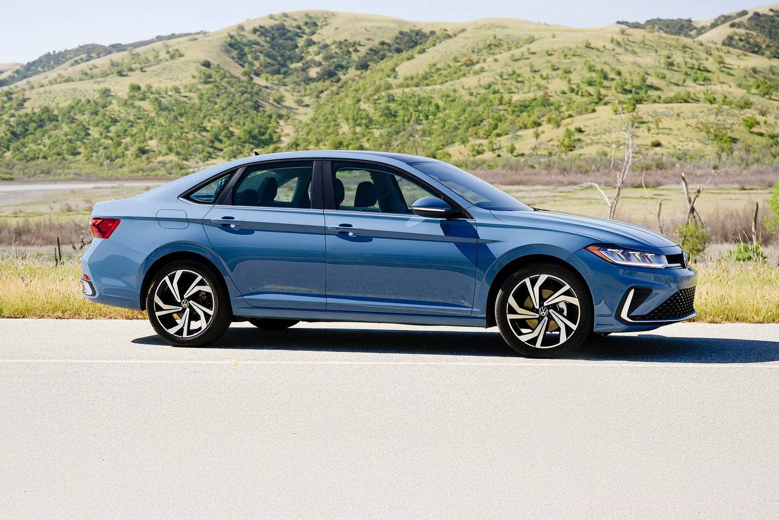 A blue jetta sitting on the road.