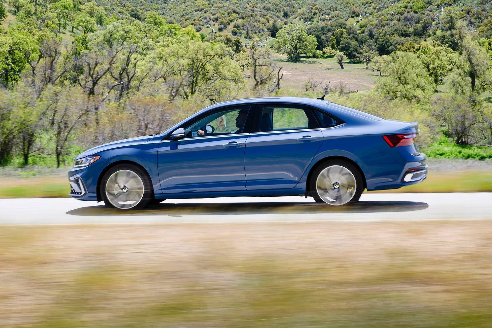 A blue jetta driving along the road.