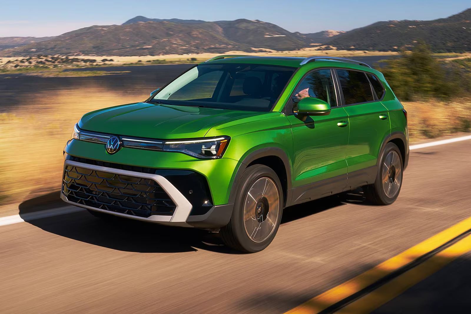A green suv driving on the street.