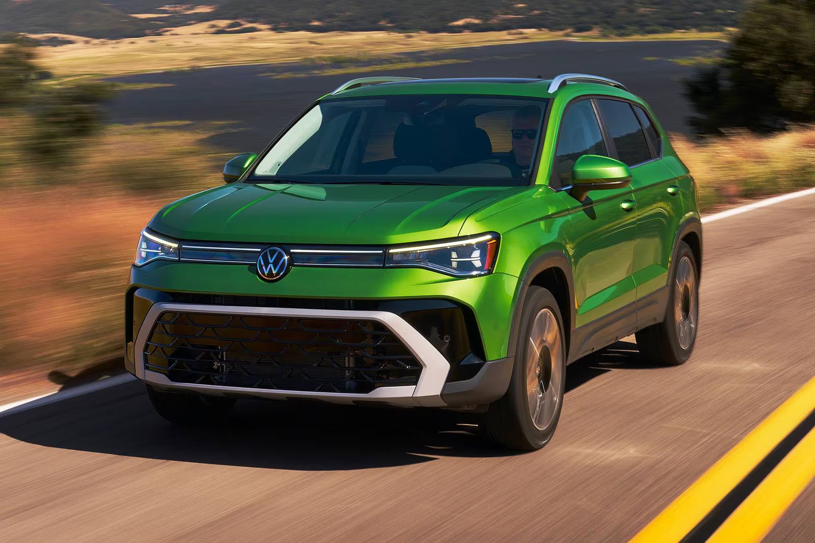 A green suv driving on the road.