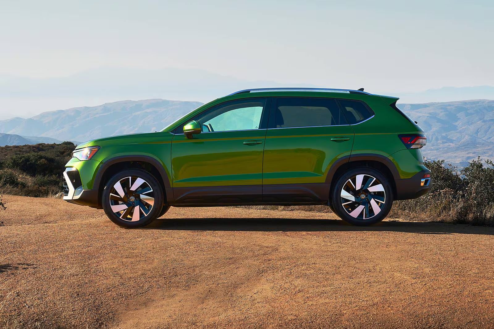 A green suv sitting parked off-road.
